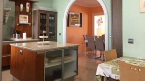 A kitchen with a central island, a dining area with chairs, and a wall-mounted cabinet.
