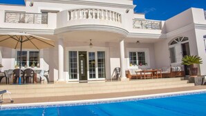A two-story building with a pool, outdoor seating, and a covered patio area.