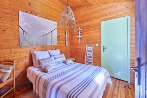 Une pièce de cabane en bois comprenant un lit, un luminaire suspendu, une porte et des éléments décoratifs sur les murs.
