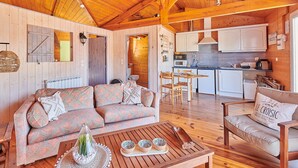 A cozy cabin interior with a wooden ceiling, a sofa, a dining table, and a kitchen area. - Gîte Escale Bien Etre in Biscarrosse (Biscarrosse)