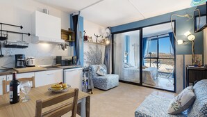 A modern kitchen with a dining area, a sofa, and a view of the outdoors.
