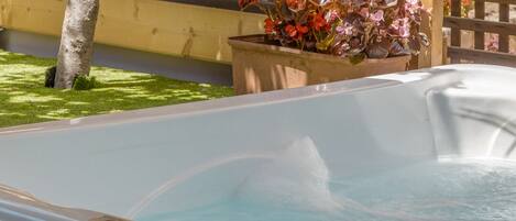 A hot tub with a wooden deck and a wooden fence in the background.