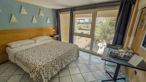 A hotel room with a bed, a small table with a pitcher and glasses, a nightstand, and a view of the outside through a large window. - b&b Domus Vesuvia (Torre Annunziata)