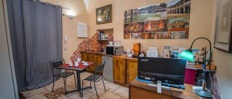 A compact kitchen with a dining area, a small refrigerator, a microwave, and a sink.
