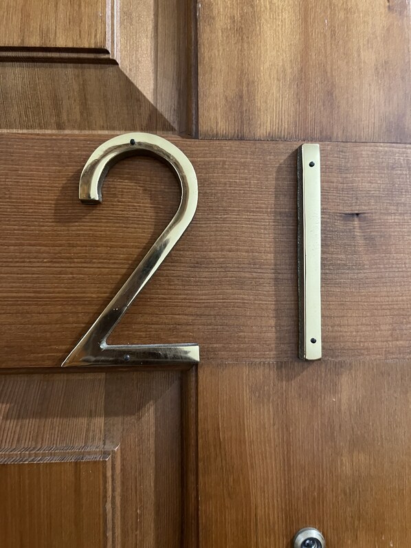 A wooden door with a brass number plate displaying the number 21.