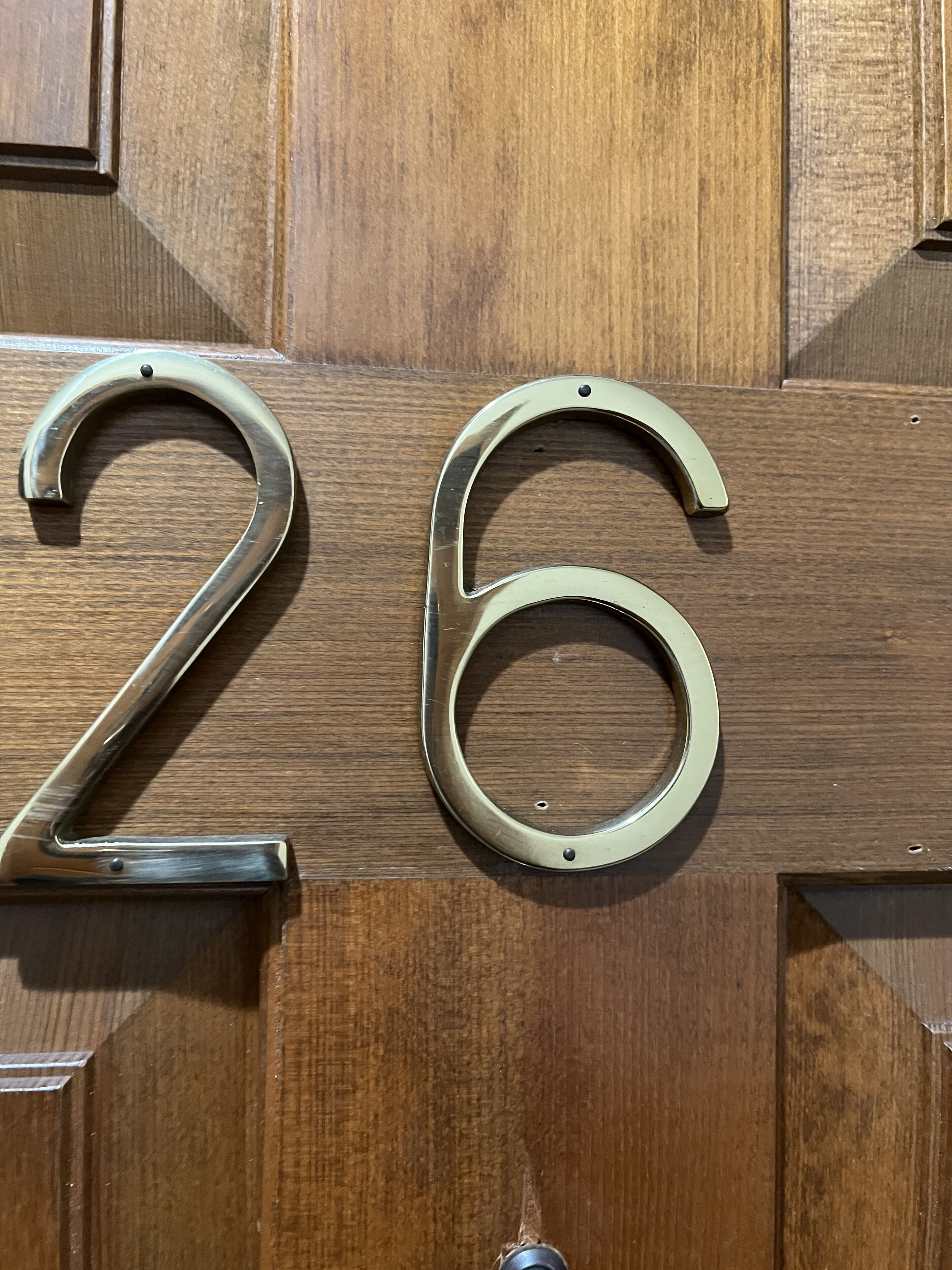 Eine Holztür mit einem Messingschild mit der Nummer 26.