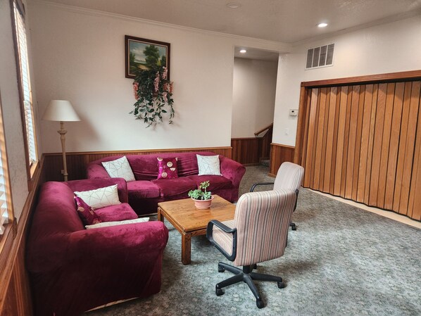 Una sala de estar con un sofá rojo, un sillón a rayas y una mesa de centro de madera.