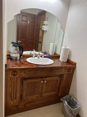 A wooden bathroom vanity with a sink, mirror, and storage cabinet.