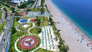 Vista aérea de una zona costera con playa, pista de atletismo y parque con diversas instalaciones.