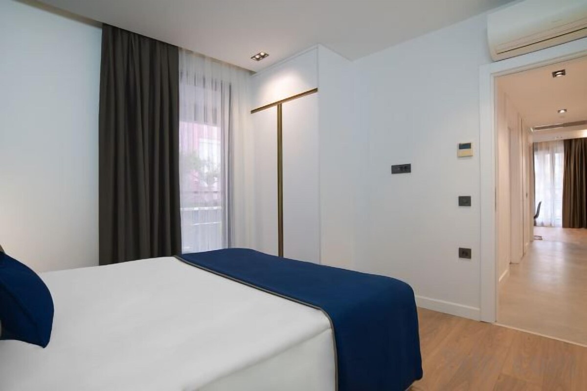 Una camera d'albergo con un letto, un armadio, uno specchio e una porta che dà su un corridoio.