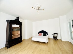 A minimalist bedroom with a bed, a wardrobe, and a chair. - Historical building in the heart of the city center  (Napoli)