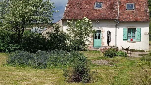 A traditional house with a red-tiled roof, a white facade, and green shutters.