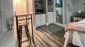 A compact room with a kitchenette, a dining area with a stool, and a bed with a blanket. - Thomas Mill Creek Lakefront Property  (Abbeville)