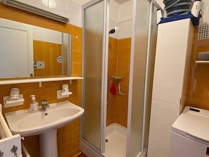 A bathroom with a shower, sink, and a mirror.