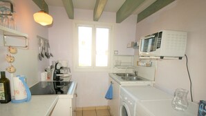 Een kleine keuken met een wasmachine, een magnetron en een koffiezetapparaat.