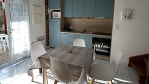 Cozinha moderna com armários azuis, micro-ondas e máquina de lavar louça. Há uma mesa de jantar com quatro cadeiras.