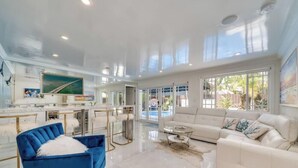 Un amplio salón con un ventanal grande, un sofá, un sillón azul y un televisor.