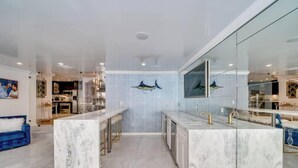 Una cocina moderna con encimeras de mármol, una zona de bar y un comedor con sofá azul.