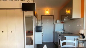 A compact kitchen with a dining area, a built-in TV, and a coffee machine. - Bright studio with balcony, Wi-Fi, air conditioning, near park (Balaruc-les-Bains)
