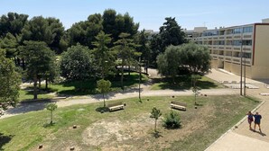 A courtyard with trees, benches, and a building with multiple balconies. - Bright studio with balcony, Wi-Fi, air conditioning, near park (Balaruc-les-Bains)