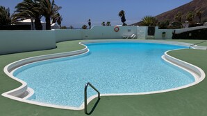 A swimming pool with a wavy edge design, surrounded by a green deck. - Relaxing Private Villa a Short Walk From Seafront (Playa Blanca)