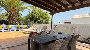 An outdoor patio with a table and wicker chairs, a pool, and lounge chairs. - Relaxing Private Villa a Short Walk From Seafront (Playa Blanca)