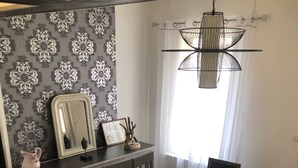 Ein Essbereich mit Holztisch und Stühlen, einer Pendelleuchte, einem Spiegel und einer Wand mit Muster.