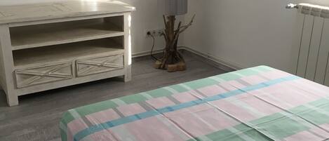 Un dormitorio con cama, cómoda, lámpara y radiador.