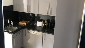 Eine kleine Küche mit grauen Schränken, einer schwarzen Arbeitsplatte und einem Holzboden.