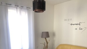 Ein modernes Wohnzimmer mit einem gelben Sofa, einem dunklen Sessel, einem runden Couchtisch, einer stehenden Lampe und einer Wand mit einem motivierenden Zitat.