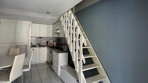 Une cuisine moderne avec des meubles blancs, un coin repas comprenant une table et des chaises, et un escalier avec des rampes blanches.