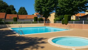 Une piscine rectangulaire dotée de deux échelles, entourée d’une terrasse carrelée.