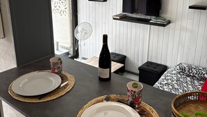 A modern kitchen with a dining area, a bottle of wine, and a television on the wall. - Holiday pavilion 4 pers., parking, aircon, near beach (Argelès-sur-Mer)