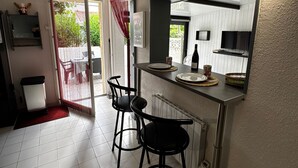 A compact kitchen with a dining area, a sliding glass door leading to an outdoor patio, and a small bar counter. - Holiday pavilion 4 pers., parking, aircon, near beach (Argelès-sur-Mer)