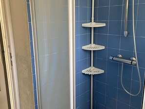 Ein Badezimmer mit blauen Fliesenwänden, einer Dusche mit Duschbrause und einem Duschschlauch.