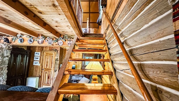 A wooden staircase leading to a loft bedroom with a bed and a window. - Off-grid Cabin at Angel Valley Ranch (Duck Creek Village)