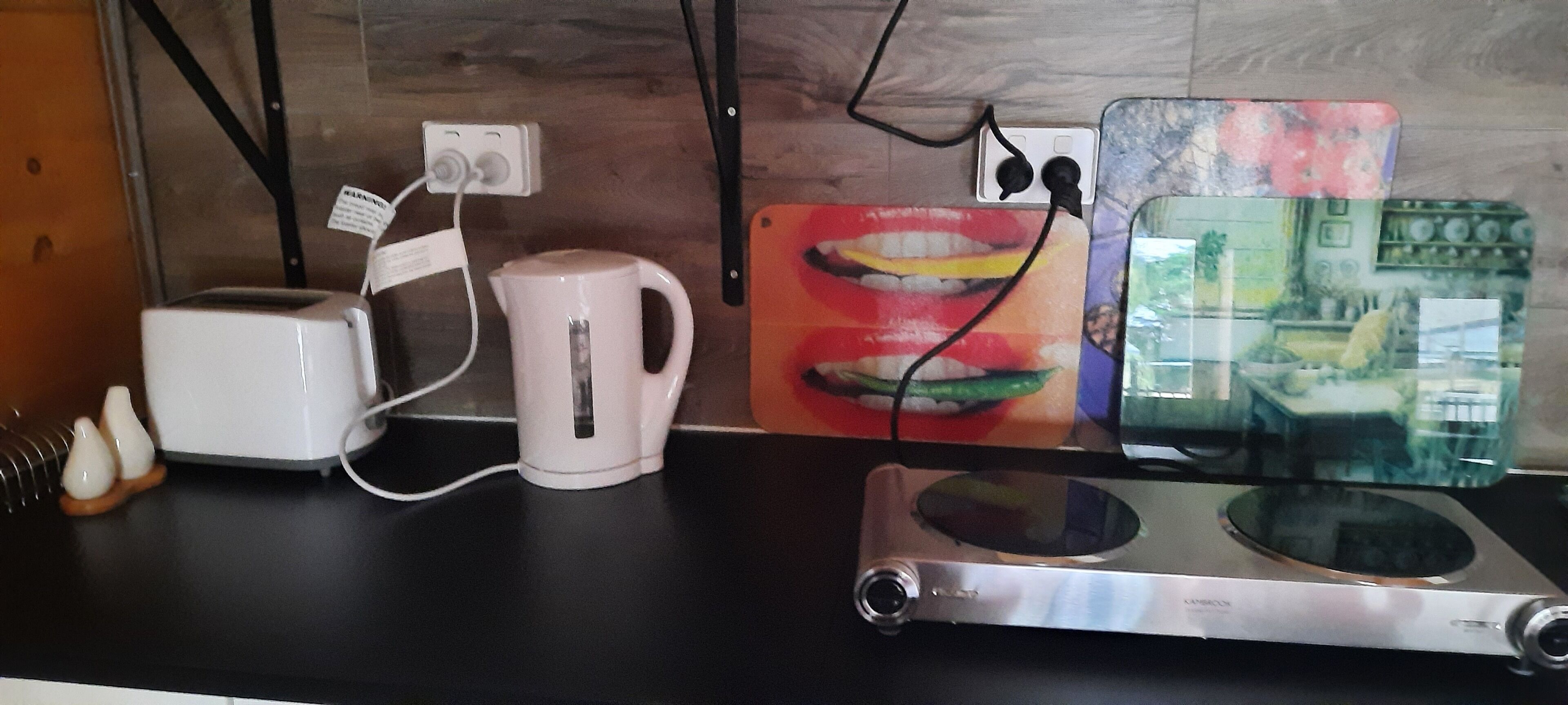 Un piano di lavoro in cucina con un tostapane, una tazza bianca, una caffettiera in vetro e un frullatore.