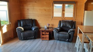 A cozy room with two leather chairs, a small wooden table, and a wooden bench.