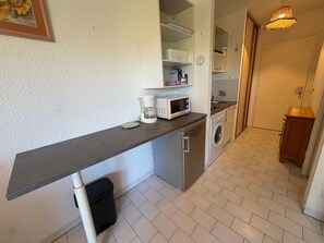 Una cucina compatta con forno a microonde, macchina del caffè e lavatrice.