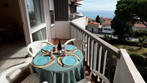 A balcony with a table set for two, overlooking a coastal view. - Apartment at Racou 100m from the beach with pool and parking (Argelès-sur-Mer)
