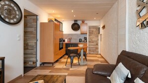 Un espace de vie compact comprenant un coin cuisine, un coin repas et un espace détente avec un canapé et une table basse.