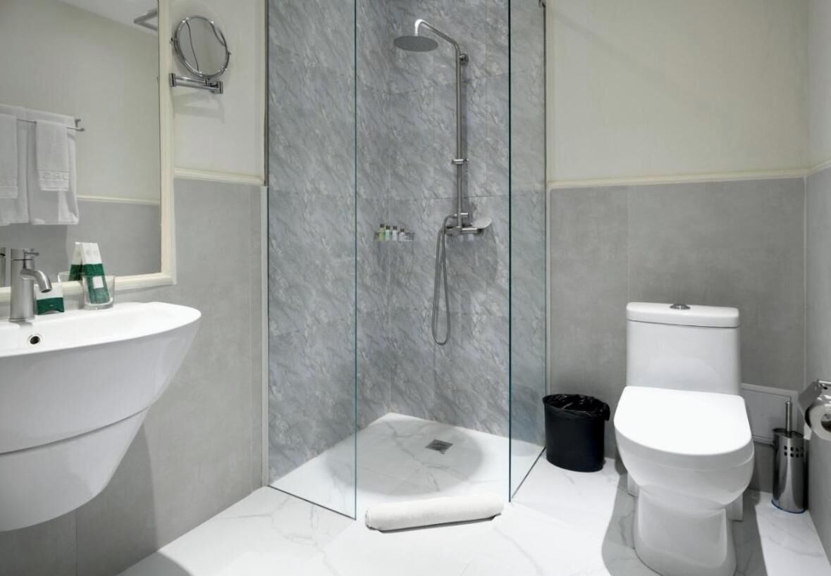 Een moderne badkamer met een douchecabine van glas, een wit wastafelmeubel en een toilet.