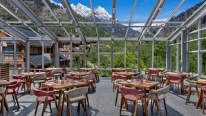 A restaurant with tables and chairs arranged in a spacious, open layout, overlooking a mountainous landscape. - Welcomhotel By ITC Hotels Hamsa Manali (Manali)