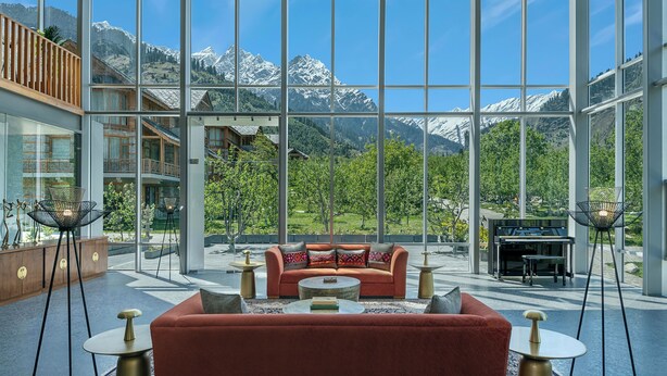 A modern interior with a red sofa, round coffee table, and a piano in the background. - Welcomhotel By ITC Hotels Hamsa Manali (Manali)