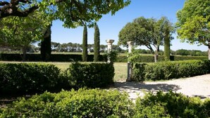 Un jardin avec des haies soigneusement taillées, un sentier et une construction en pierre.