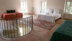 Une chambre  à coucher avec un lit, une petite table, une chaise, une fenêtre et un escalier en colimaçon.
