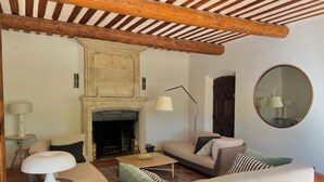 Un salon avec une cheminée, des canapés, une table basse et un miroir rond.