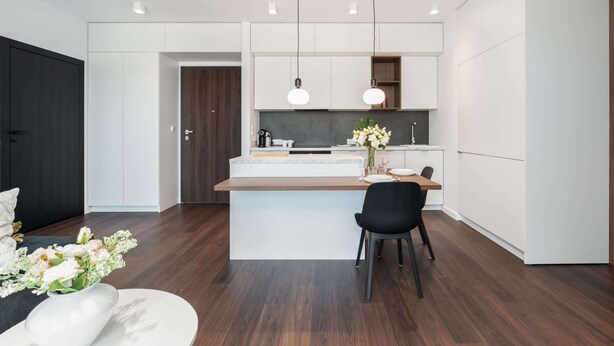 A modern kitchen with white cabinetry, a central island, and pendant lighting. - Cozy Apartment | Garage Parking and Balcony (Poznan)