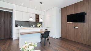 A modern kitchen with white cabinets, a wooden countertop, and pendant lighting. - Cozy Apartment | Garage Parking and Balcony (Poznan)