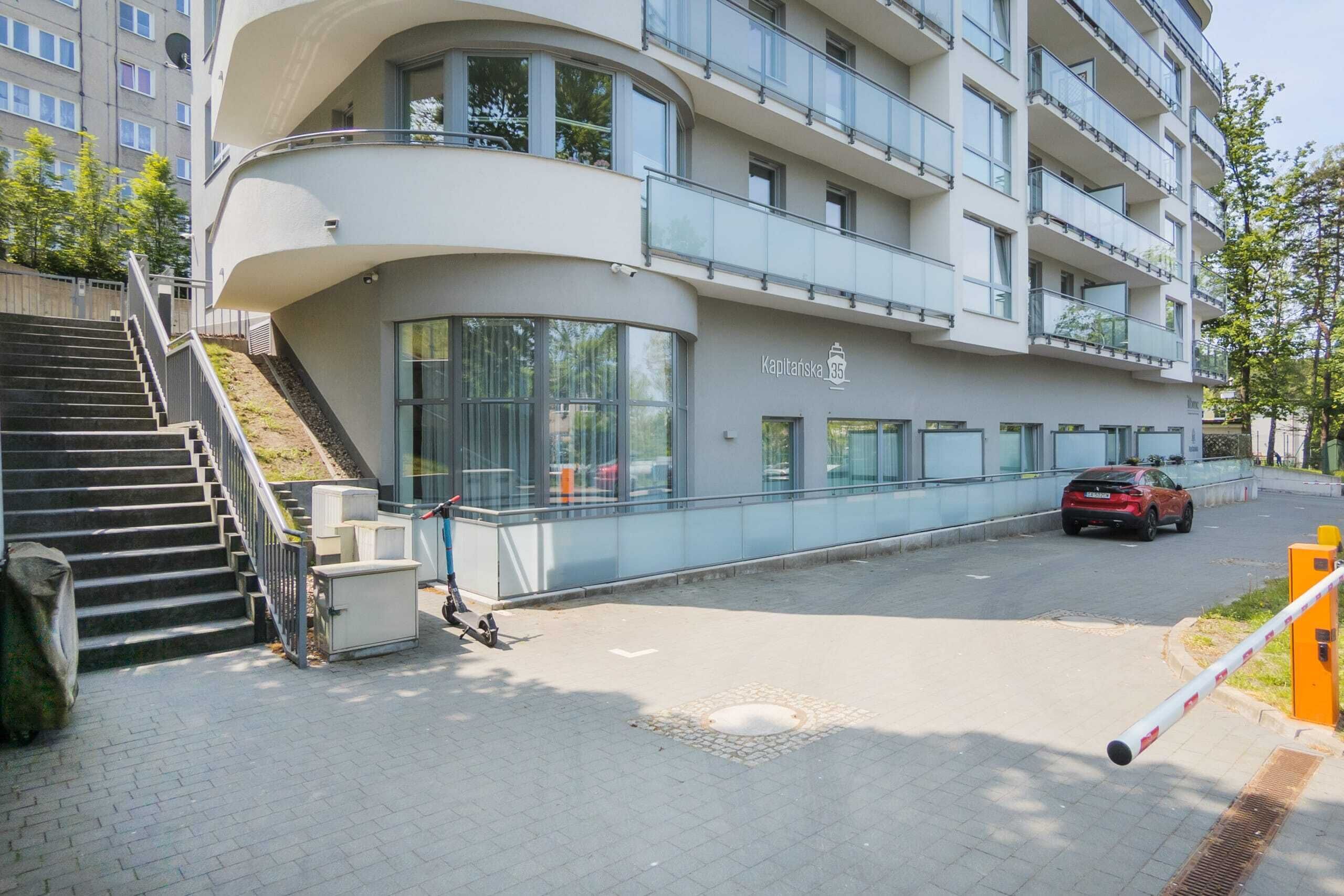Ein modernes Mehrfamilienhaus mit gewölbter Fassade, einer sichtbaren Treppe und einem Auto auf der Straße.